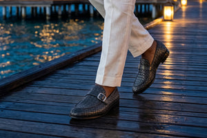 Person wearing brown loafers on a wooden dock by water