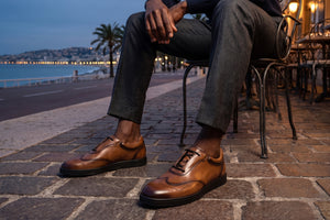 Man sitting at street side cafe with brown leather shoes on